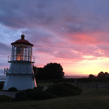 Lighthouse with flag_sunset_square